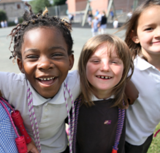 Two young girls in uniform mimicking toothbrushing with carboard brushes