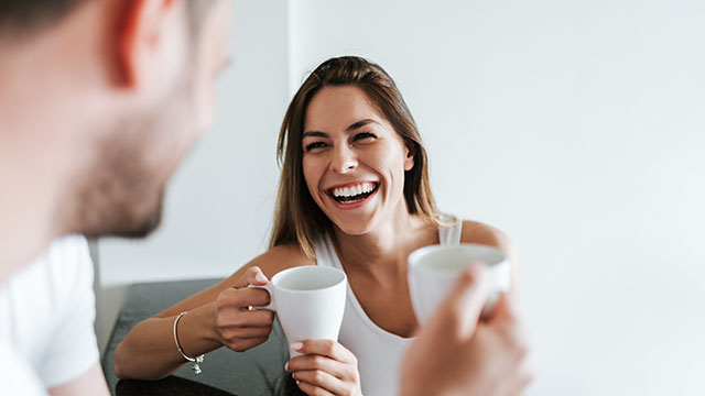 A happy couple holding white cups indoors