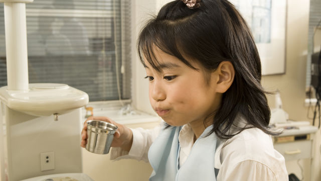 girl rinsing her mouth at the dentist