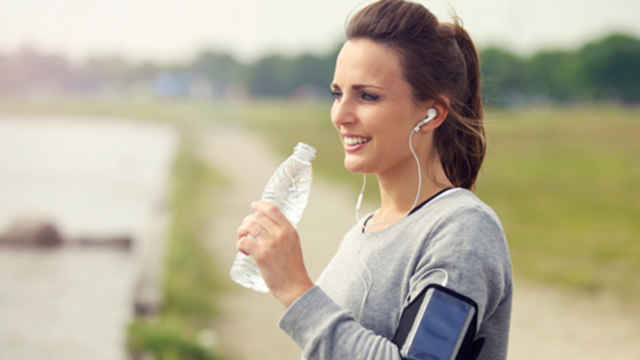 woman drinking water after running