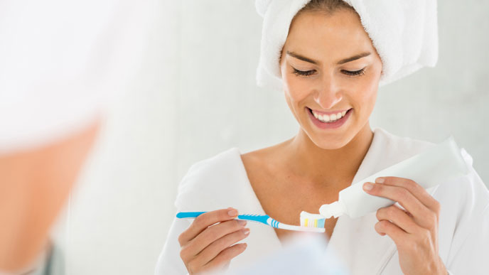 Woman putting toothpaste on her toothbrush